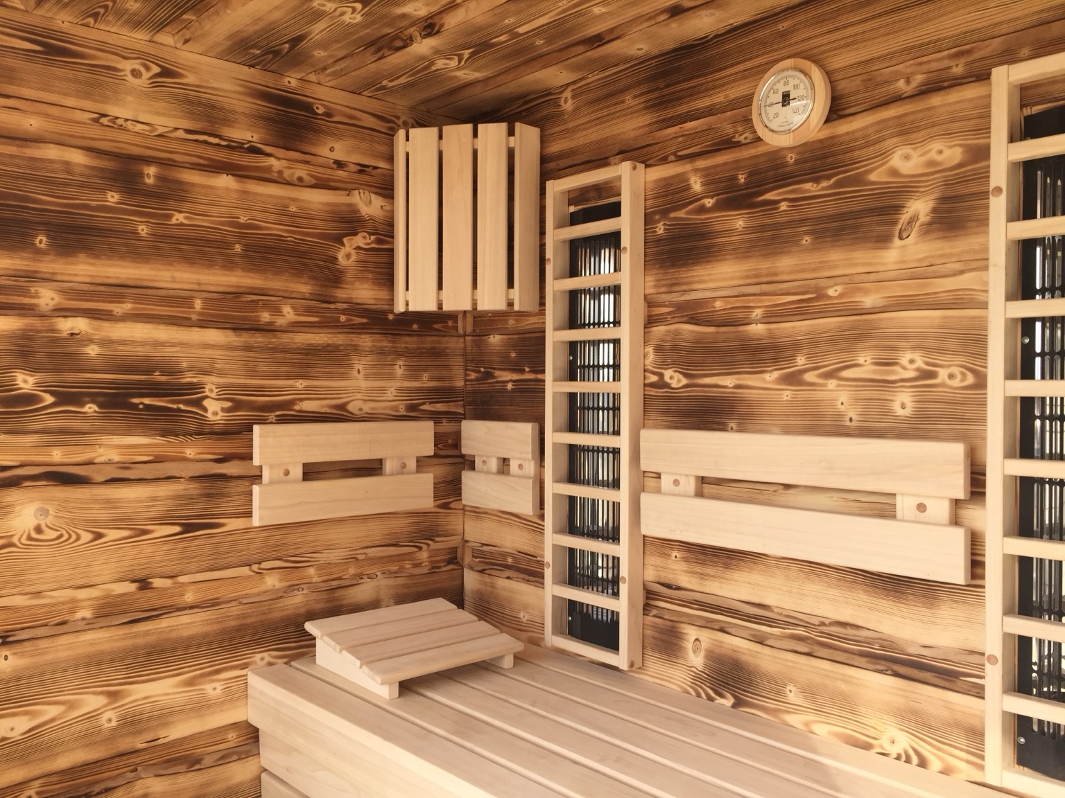 Sauna mit charaktervollen Holzoberflächen und maßgefertigten Bänken.