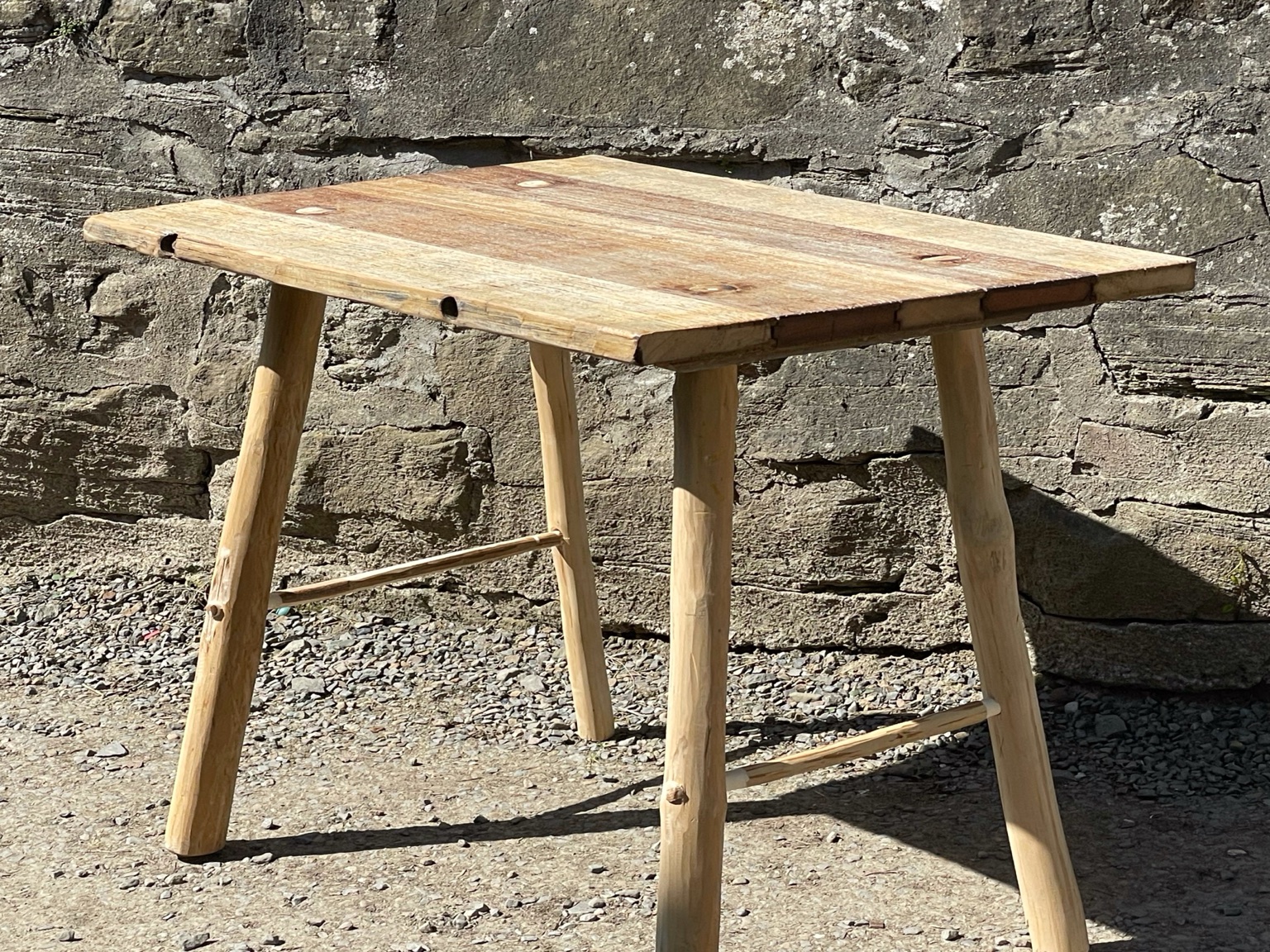 Tisch mit Holzplatte und einem Gestell aus naturgeformten Hölzern.